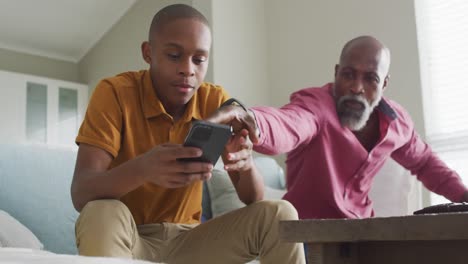 Video-of-nervous-african-american-father-taking-his-son-smartphone-and-yelling