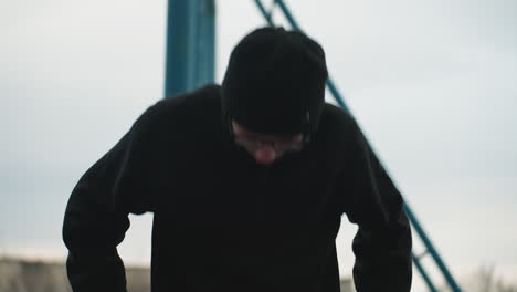 close-up of a young boy working out on a metal bar, dressed in a black outfit and glasses