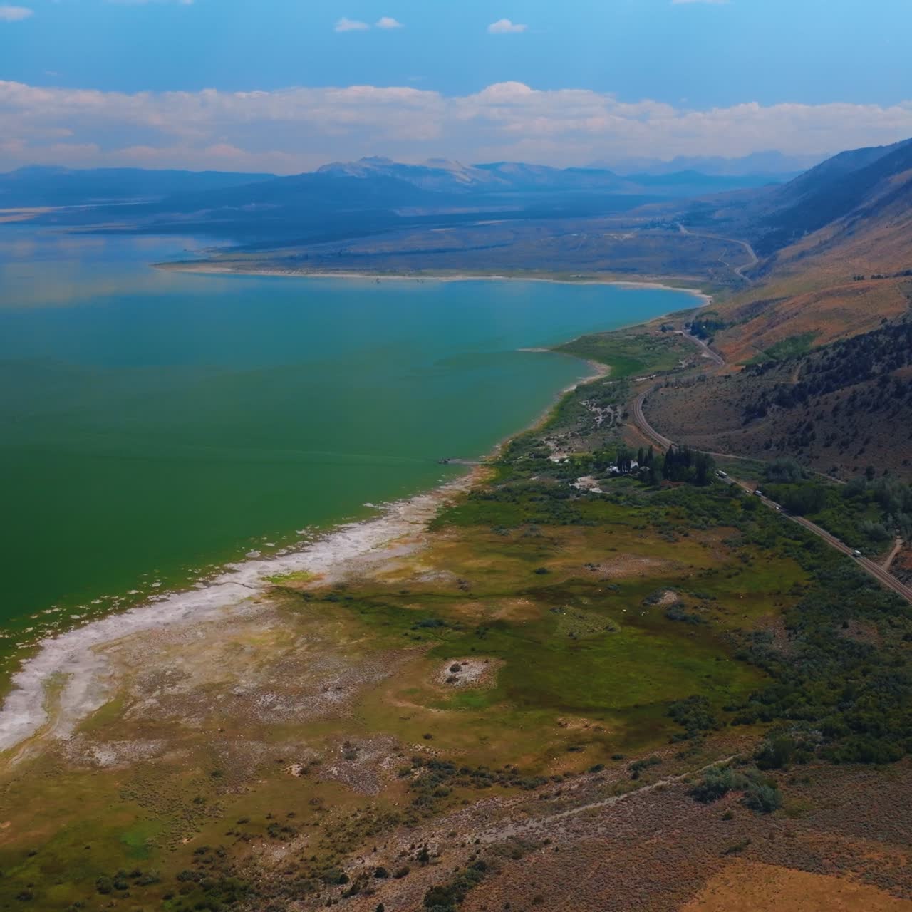 Lovely eye-catching scenery of Mono Lake, California, USA. Motorway passing between the beautiful lake and mountains. White clouds at backdrop