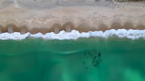 A-birds-eye-view-looking-down-on-Maslin-Beach,-a-beautiful-white-sand-beach-with-bright-blue-ocean-waters-in-South-Australia