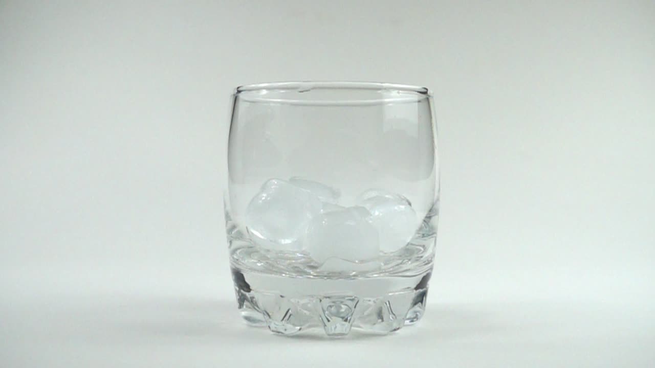 IJsblokjes vallen in een glas. Slow motion.