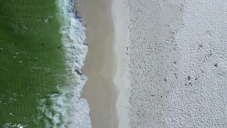 waves crashing peacefully on sandy beach - vertical aerial footage