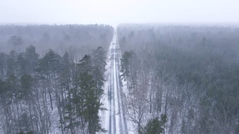 Vista-Asombrosa-De-La-Carretera-Cubierta-De-Nieve-Y-El-Paisaje-Forestal-En-Medio-De-Un-Día-De-Invierno-Nevado---Toma-Aérea