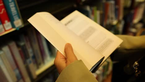 person flipping through a book in library