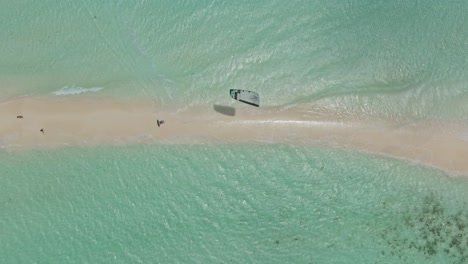 una foto de arriba de un kitesurfista saltando el puente de tierra de cayo agua en los rocas, venezuela