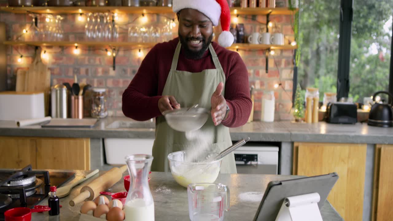 Flour pouring from red cup, Santa-hatted cook on counter is sifting, whisking batter for baking