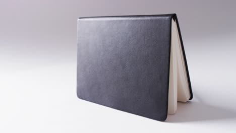 close up of open black book standing horizontal with copy space on white background in slow motion