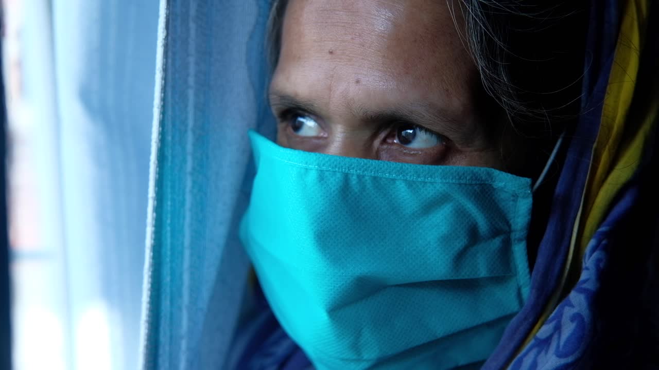 mujer mayor con una máscara en una ventana