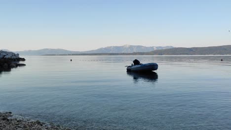 Static shot of boat in the sea with mountains in background on sunset in Croatia
