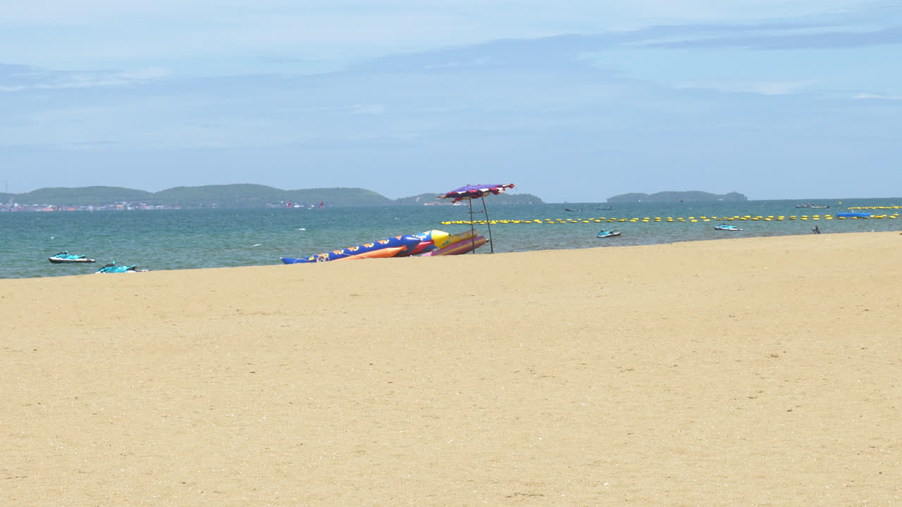 Picturesque sunny day at the beachfront of Pattaya, facing the Gulf of Thailand, with mountains and business centers at a far distance across the sea of Chonburi province