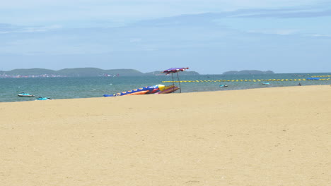 Picturesque-sunny-day-at-the-beachfront-of-Pattaya,-facing-the-Gulf-of-Thailand,-with-mountains-and-business-centers-at-a-far-distance-across-the-sea-of-Chonburi-province