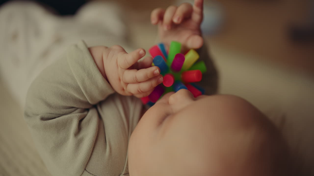 Baby Boy Chewing Rubber Ball on Blanket