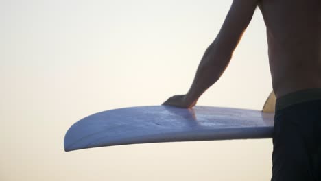 man carrying and wiping off a surfboard