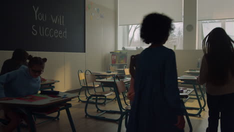 students walking in classroom at school. schoolchildren sitting at desks