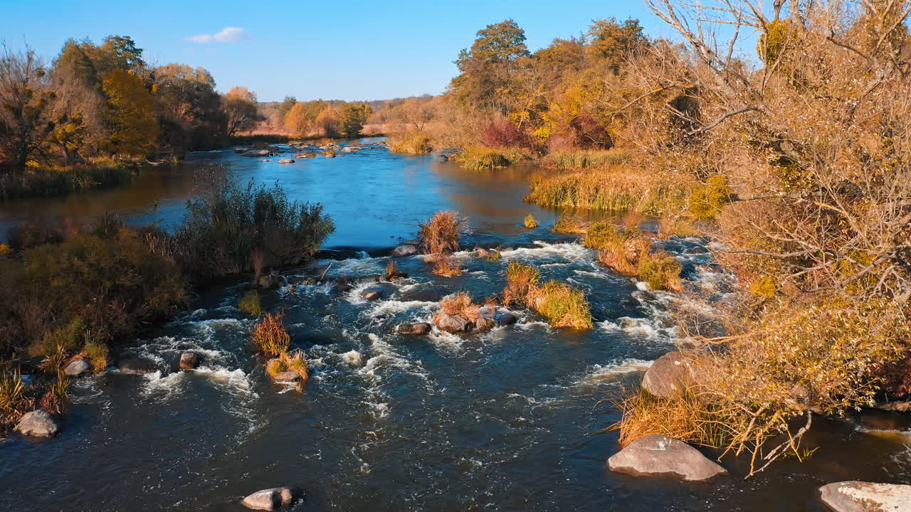 Aerial view. Flying over the beautiful autumn river. Beautiful blue sky over the water