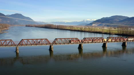 mission railway bridge with freight train crossing in mission, british columbia, canada - aerial drone shot