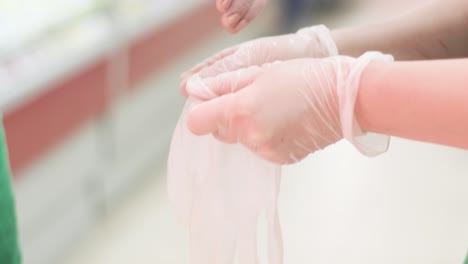 workers puts on disposable gloves in the supermarket market. close-up. slowly