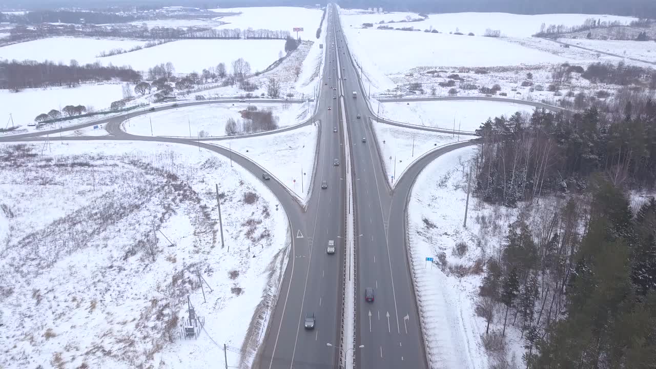 눈 속의 고속도로 교차로에서 움직이는 자동차와 트럭의 공중 전망