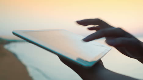 female hands using touch pad by sea
