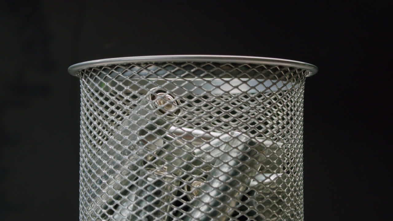 Silver batteries AA and AAA falling into wastebasket close-up. Double-A battery is a standard size single cell cylindrical dry battery. Batteries are common in portable electronic devices. Environmental impacts of lithium-ion batteries concept. An AA battery is composed of a single electrochemical c