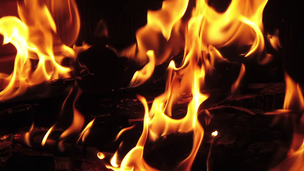 Close up of a warm fireplace with wood burning and bright flames flickering in the dark