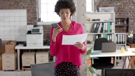 Focused-biracial-casual-businesswoman-talking-on-smartphone-and-holding-graph-in-slow-motion