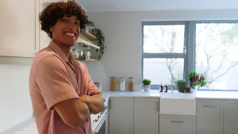 smiling man standing in modern kitchen with arms crossed, enjoying bright morning, at home
