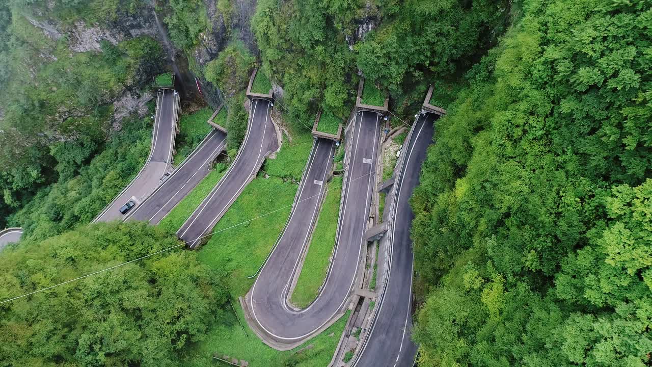 Historic cliffside road twists dramatically through tunnel hairpin bends, Italy
