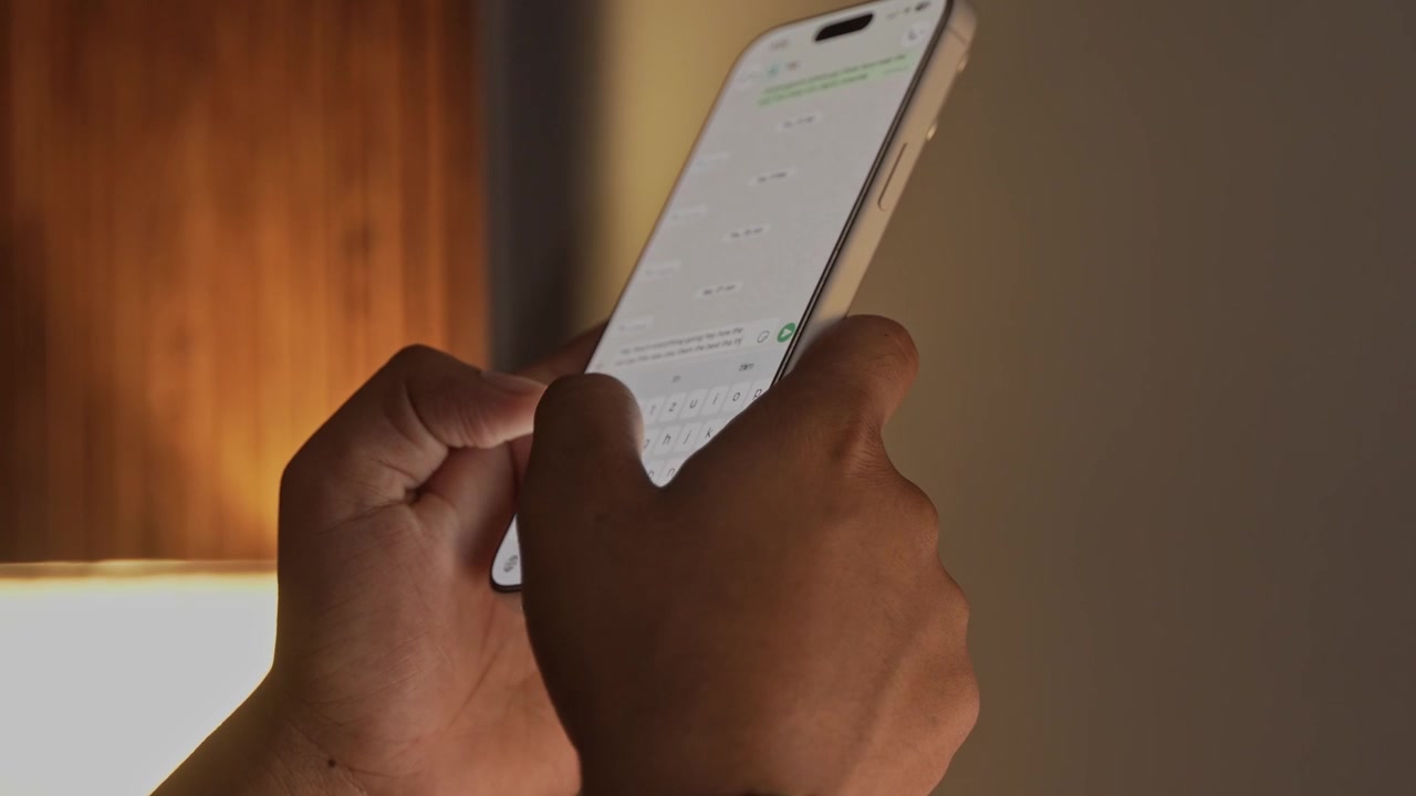Mani di uomo che chattano e digitano su smartphone, in un primo piano macro. Una persona irriconoscibile digita un messaggio di testo toccando la tastiera touchscreen, utilizzando l'applicazione WhatsApp, un social media
