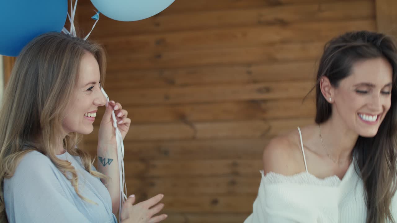 Grupo de mujeres caucásicas dando regalos a una amiga embarazada.