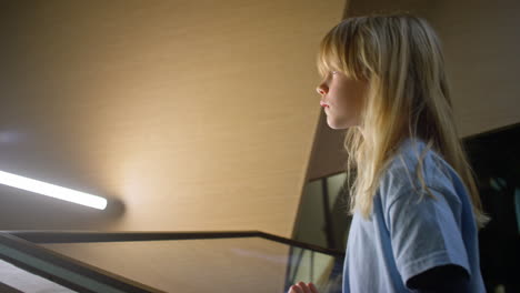 primary school girl using a touch screen display and looking around, low angle