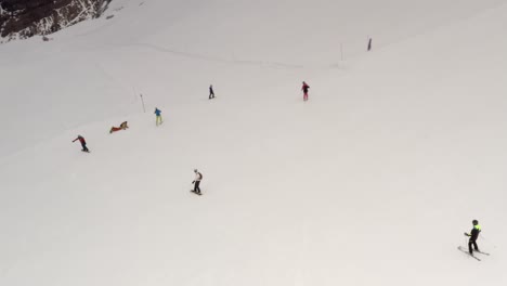 aerial view of people skiing and snowboarding on a snowy mountain slope.