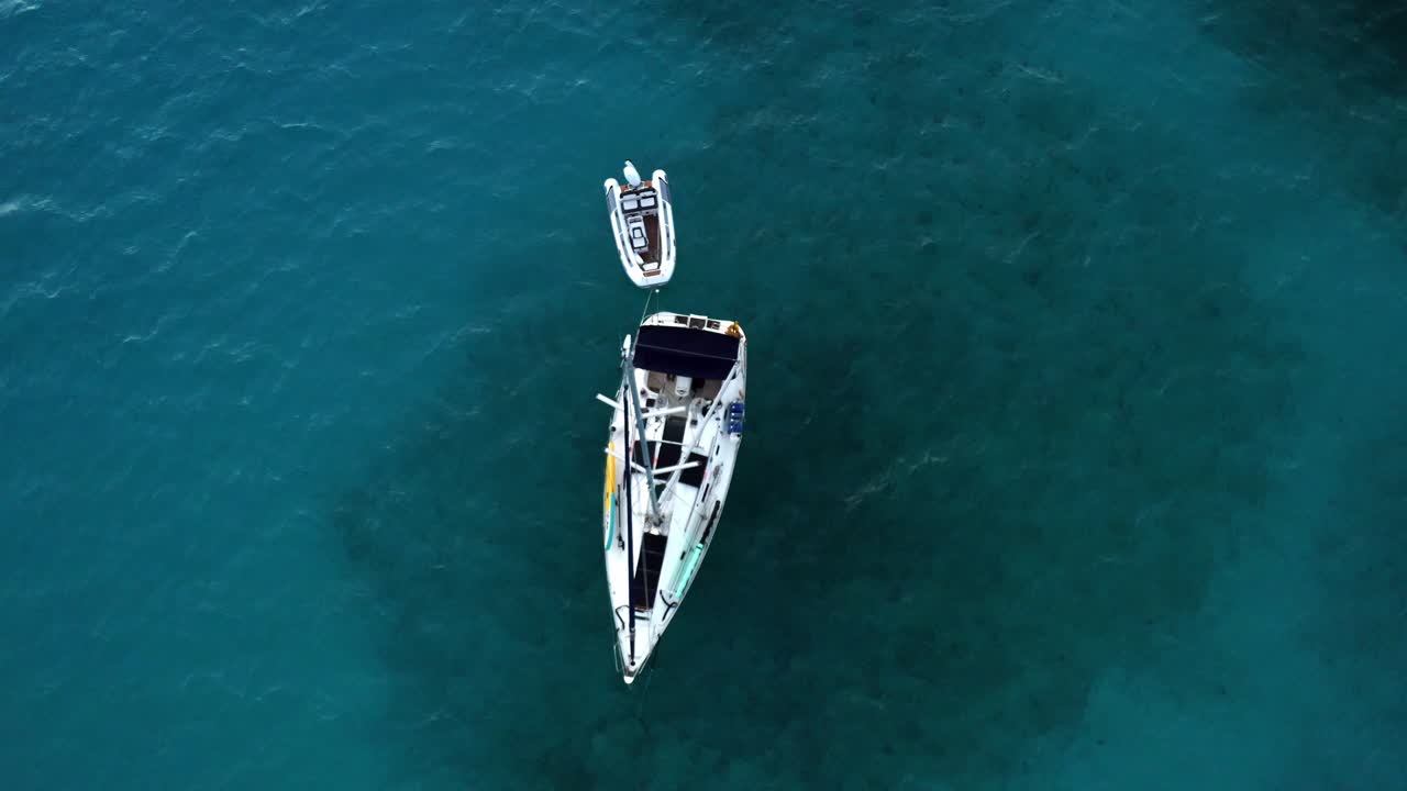 Vista aerea dall'alto di una barca a vela e un motoscafo deserti e ormeggiati nel mare tropicale