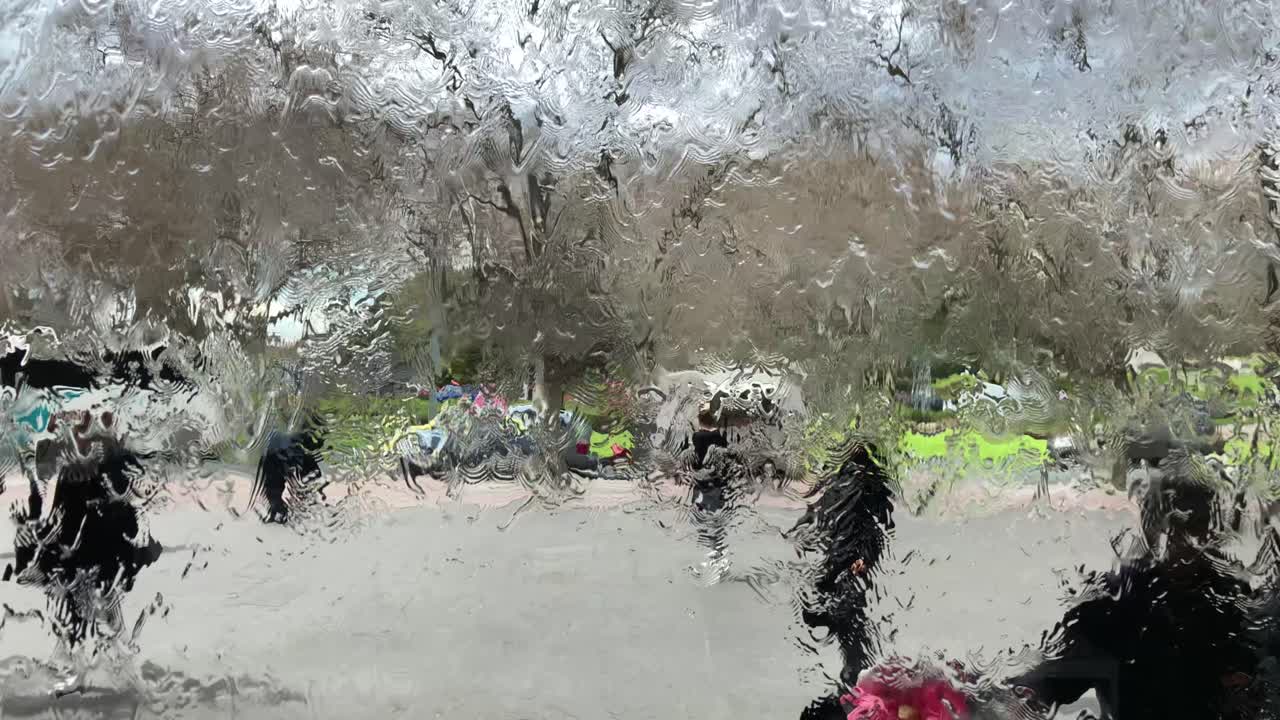 물은 유리벽을 따라 흐르고 사람들은 물이 흐르는 유리벽 뒤를 걷는다.