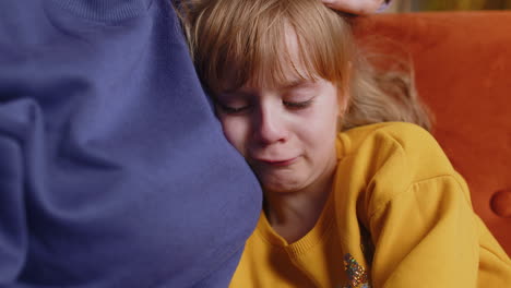 closeup of sad girl kid is crying and lying on mother at home violence against children in family