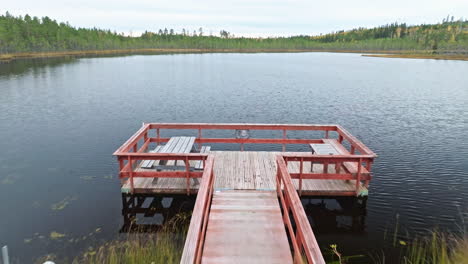 Paseo-Marítimo-De-Madera-Hasta-El-Muelle-Con-Mesas-De-Picnic-Junto-Al-Lago-Rodeado-De-Bosque-En-Suecia