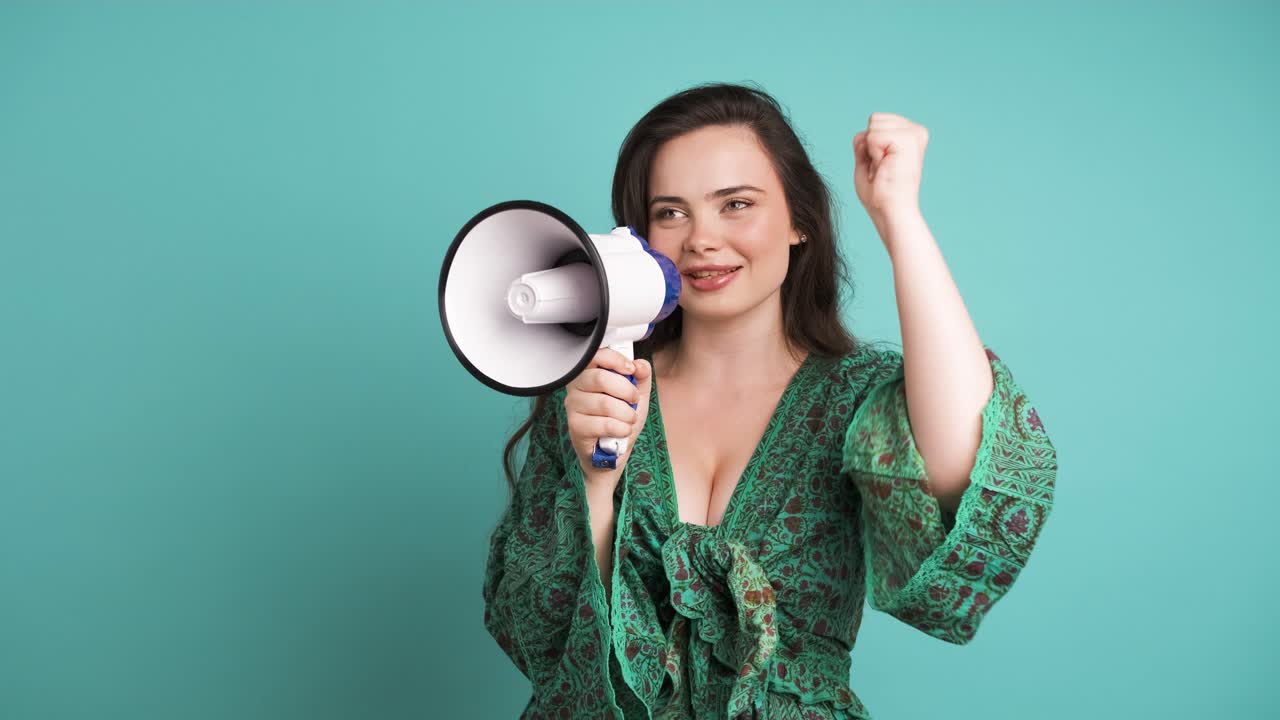 Happy woman protesting with megaphone in blue studio