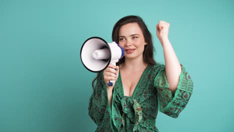 happy woman protesting with megaphone in blue studio