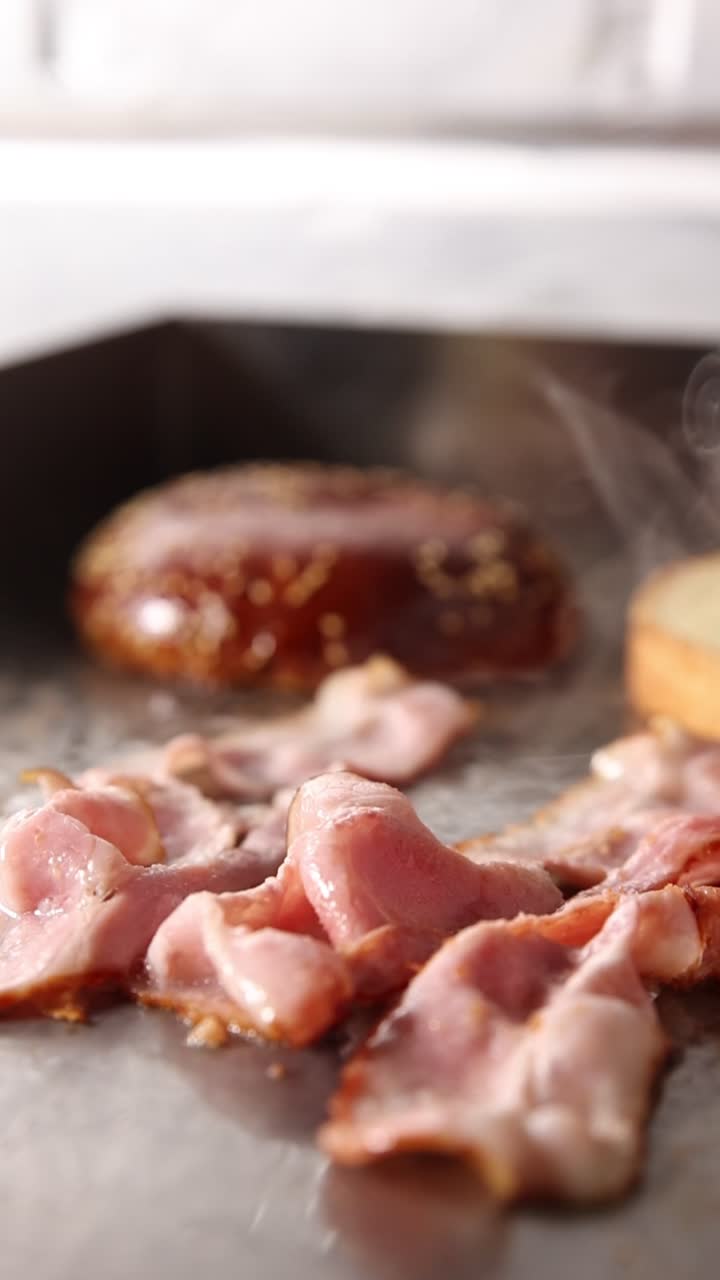 Primo piano di pancetta che frigge su una piastra calda