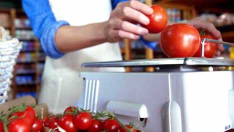 personal femenino pesando tomates en la balanza en el supermercado