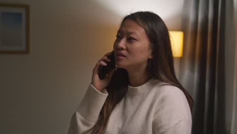 anxious or stressed woman spending evening at home walking around lounge talking on mobile phone 2