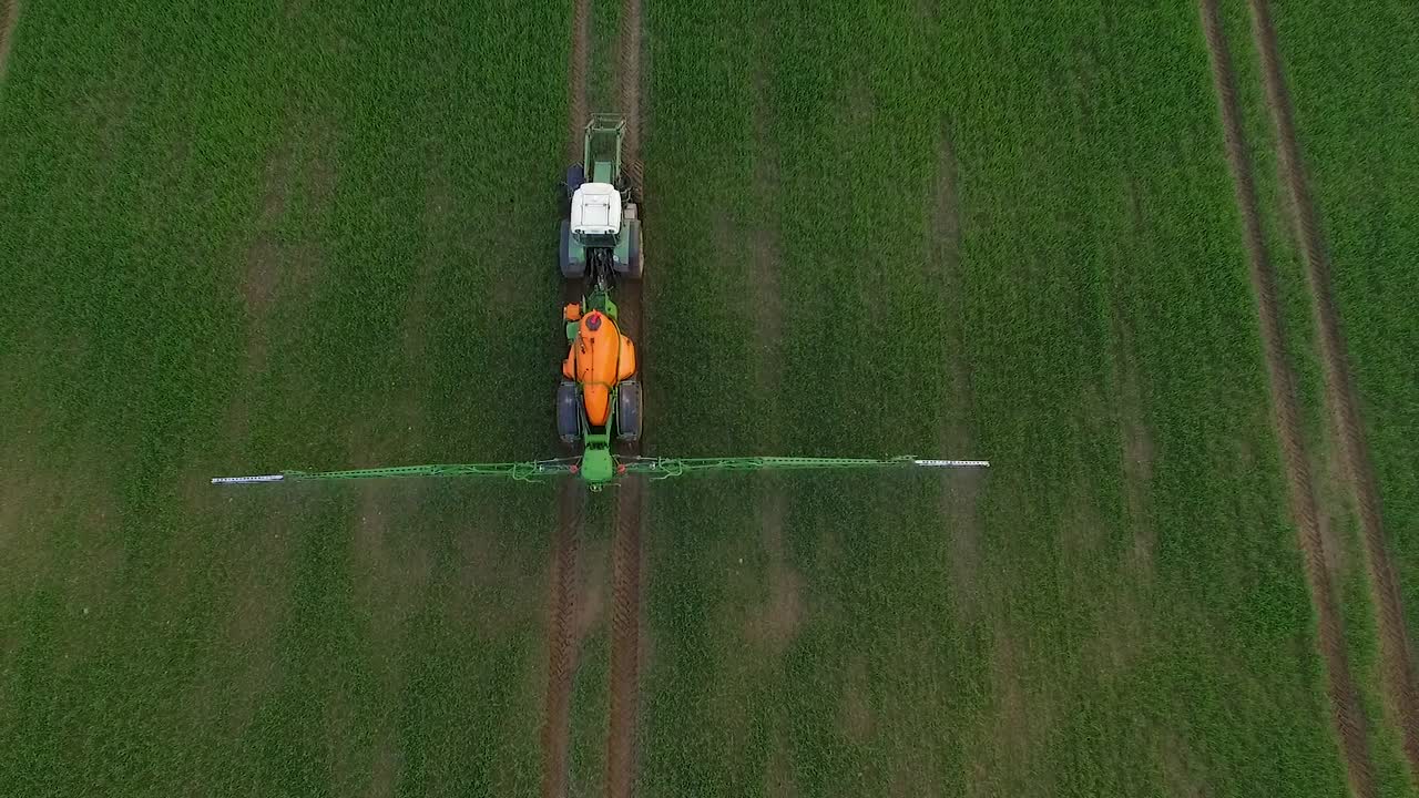 Irrorazione di pesticidi e fertilizzanti sul campo, vista aerea con trattore