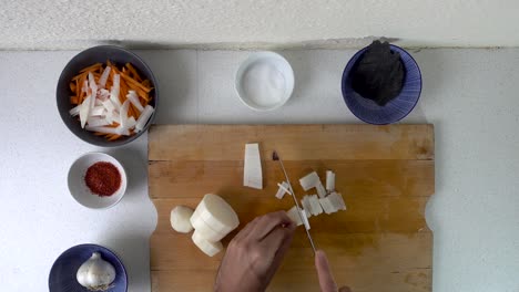 Male-hands-chopping-radish-into-small-strips,-preparing-for-Kimchi