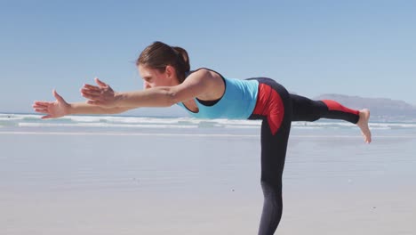 Kaukasische-Frau-Macht-Yoga-Position-Am-Strand-Und-Blauer-Himmel-Im-Hintergrund