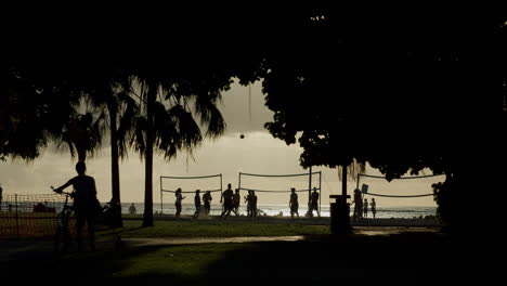 silhouettes of people playing beach volleyball at sunset