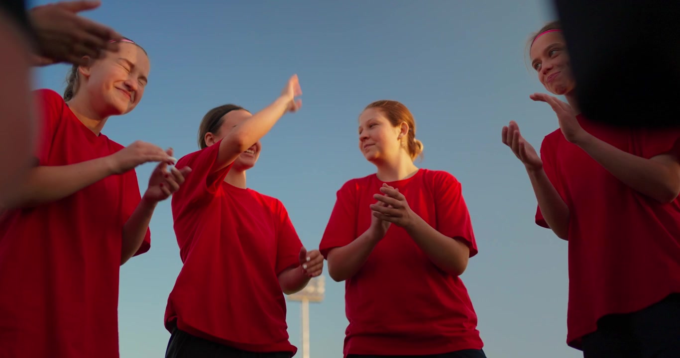 Young Female Athletes Talking, Clapping, and High-Fiving on Sports Field