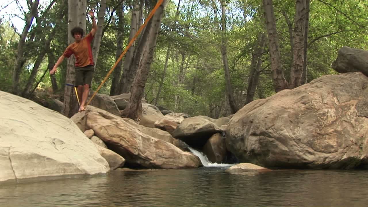 jibup de un joven slackline a través de un plácido agujero de natación