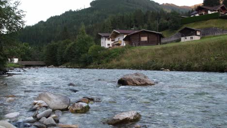 Zeitraffer-Von-Natürlichem-Bachwasser,-Das-Neben-Einer-Idyllischen-Landschaft-Mit-Häusern-Fließt