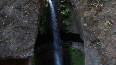 mujer corre detrás de una cascada rodeada por una pared de roca, levada do moinho