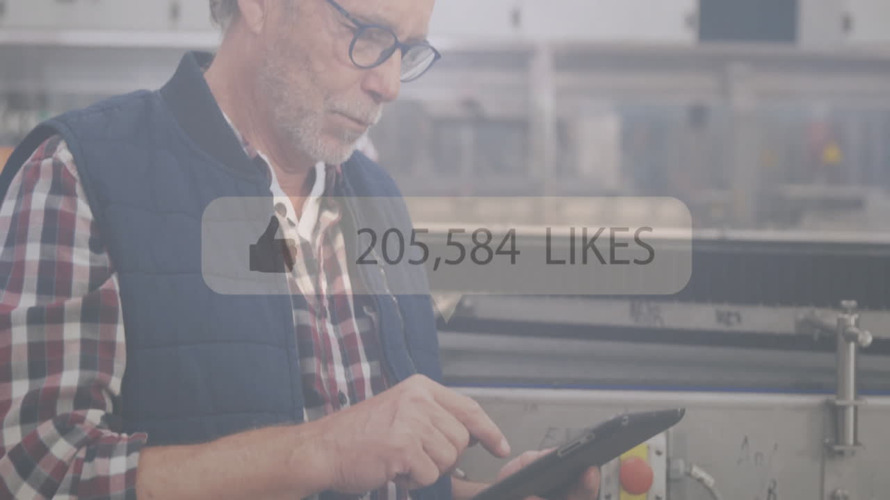 Using tablet, man in industrial setting with social media likes animation overlay